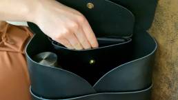 Eine Frau öffnet den Rucksack, um etwas aus der Tasche zu holen.